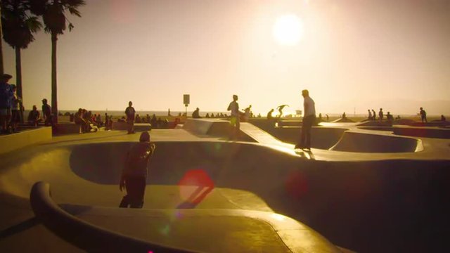 Slow motion shot of skateboarder and rollerblader in skate park near Venice Beach, California