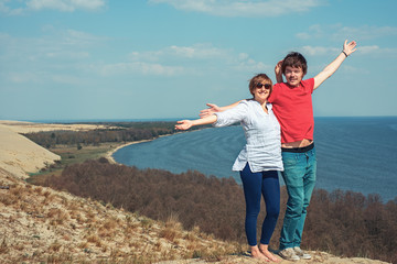 Happy man and woman are standing on the mountain