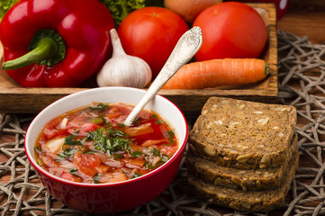 Borscht - traditional russian and ukranian beetroot soup in red bowl on wooden background.