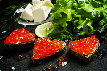 Sandwiches with black rye bread, butter and red salmon caviar on