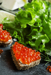 Sandwiches with black rye bread, butter and red salmon caviar on