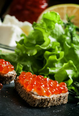 Sandwiches with black rye bread, butter and red salmon caviar on