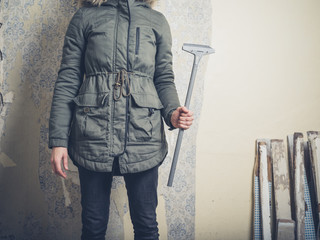Young woman with wallpaper scraper