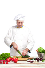 Chef cutting a green cucumber in his kitchen