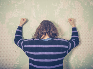 Frustrated young woman banging wall