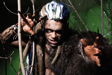 Werewolf with long nails and crooked teeth among the branches of