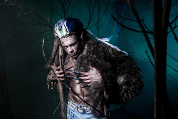 Muscular werewolf with dreadlocks with long nails among the bran