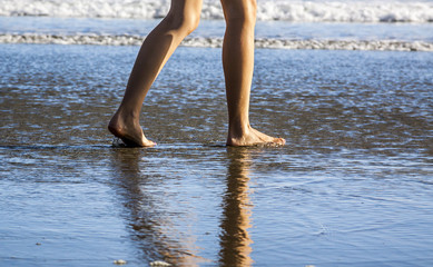Young Woman's Feet Walking in the Sand and water