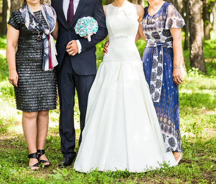newlywed couple  with guests  in green sunny park