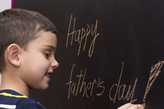 Adorable seven year old boy with board displaying Happy Father's