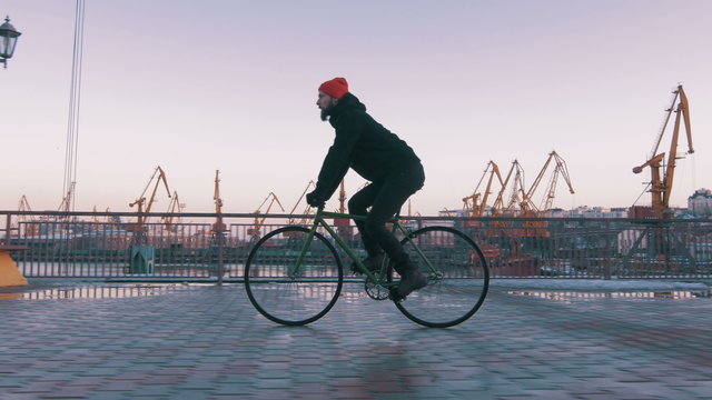 Guy riding fixied gear bike on background of the port, 4k