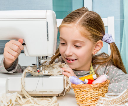smiling little girl at the table with sewing machine