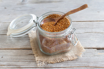 Raw brown millet in a glass jar