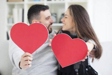 Two young dates kissing behind paper heart.Two young dates behind paper heart with their faces close to one another