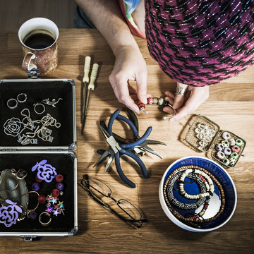 Jewelry artist making bracelet at her workshop table - square, high angle view.