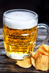 Beer with potato chips on a wooden table