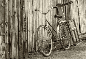 Vintage image of an old rusty bicycle near an ancient barn