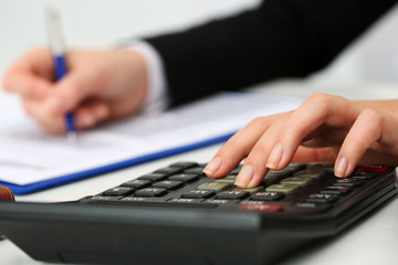 Female accountant hand holding pen counting on calculator