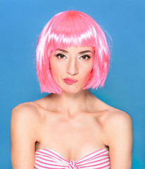 Confused young woman with pink hair on a blue background