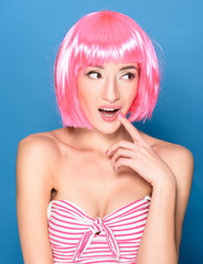 Portrait of beautiful smiling young woman with pink hair on a blue background