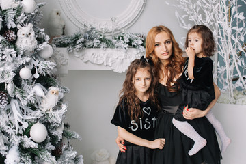 Mother with her daughters near Christmas tree