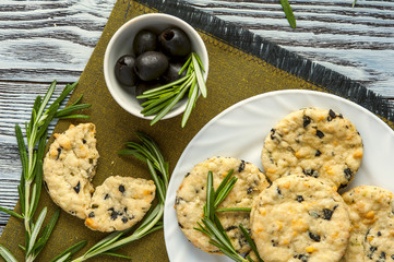 Cookies with cheese, olives and rosemary on napkin