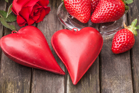 zwei Herzen, rote Rose, Erdbeeren, horizontal auf altem Holztisch