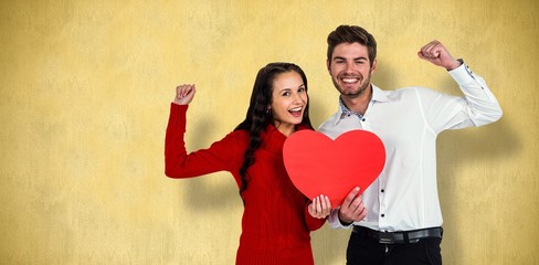 Composite image of cheerful couple holding paper heart