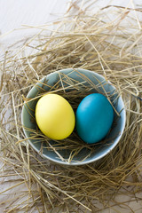 Easter eggs in straw plate on a white background