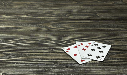 Three playing cards lie on the wooden background