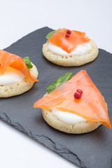 fish salmon slices on pancakes with cream, view from above on the side, close, color image. an appetizer for a party