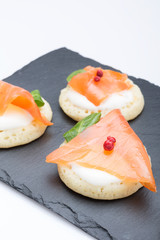 fish salmon slices on pancakes with cream, view from above on the side, close, color image. an appetizer for a party