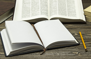 Notebook and pencil on the background of books