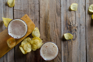Fototapeta na wymiar Glass of beer with chips on a wooden background. Top view.