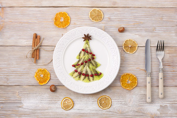 Christmas fir tree made from kiwi and pomegranate on plate. Close up view.