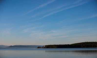 Obraz premium Lake showing the sky with clouds and reflections on mountains and clouds in the water in the heart of Yellowstone National Park near West Yellowstone, Wyoming, USA 