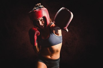 Female boxer with gloves and headgear punching