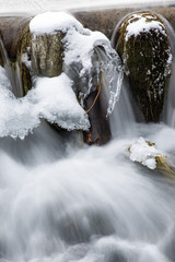 Cascatelle ghiacciate  in inverno con rocce coperte di neve