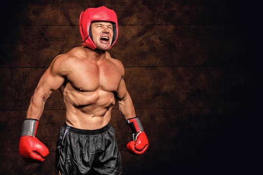 Composite image of angry boxer against black background