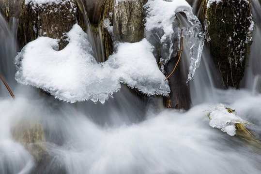Cascatelle ghiacciate  in inverno con rocce coperte di neve