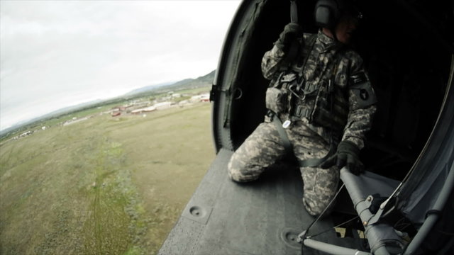 Wide angle shot from in Black Hawk helicopter flying and soldiers in the helicopter.