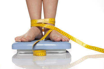 female legs on the scale and measuring tape