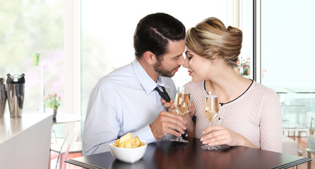 loving couple kissing sitting at a table with wine glasses