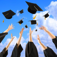 Graduates hands throwing graduation hats in the sky