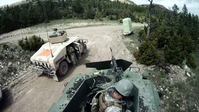 Two Solders trying to fix a gun on their humvee