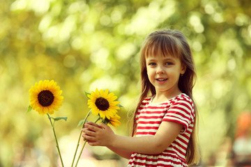 Little girl with sunflowers in the park