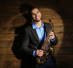 Fototapeta premium Elegant saxophonist plays jazz on wooden background