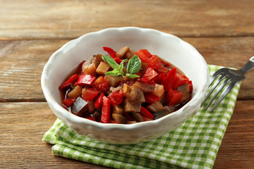 Ratatouille in bowl, on wooden table background