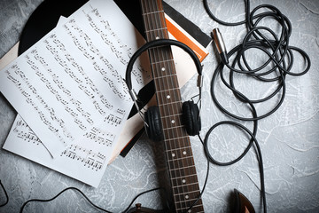 Electric guitar and headphones with music notes on grey background
