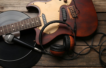 Electric guitar and headphones with microphone and vinyl on wooden background